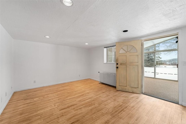 entryway featuring radiator, light hardwood / wood-style flooring, and a textured ceiling