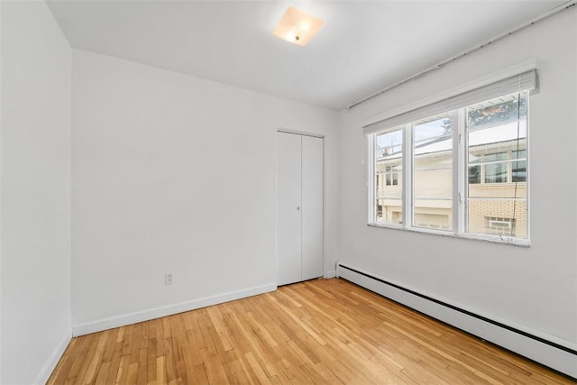 spare room with a baseboard radiator and light hardwood / wood-style flooring