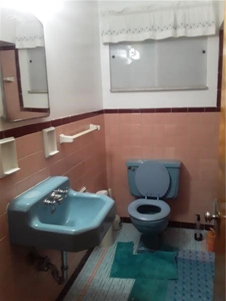 bathroom featuring tile walls, toilet, sink, and tasteful backsplash