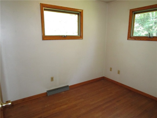 unfurnished room featuring a wealth of natural light and dark hardwood / wood-style floors