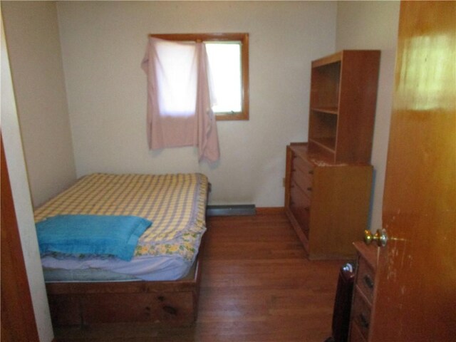 bedroom featuring a baseboard heating unit and dark hardwood / wood-style flooring