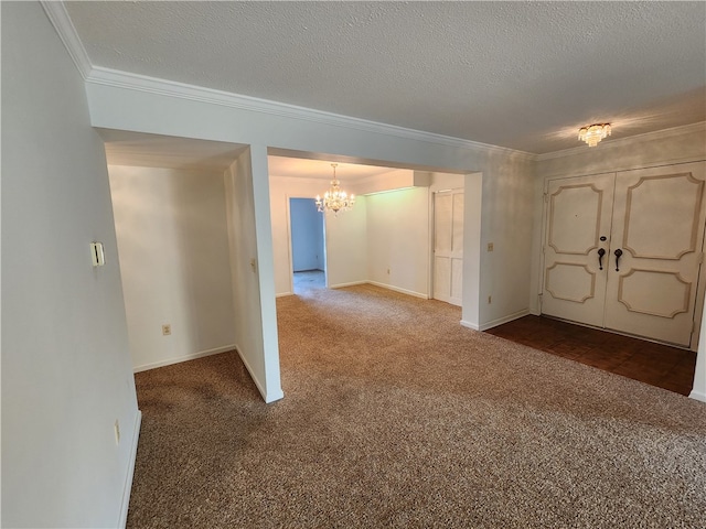 carpeted foyer entrance featuring ornamental molding, a chandelier, and a textured ceiling