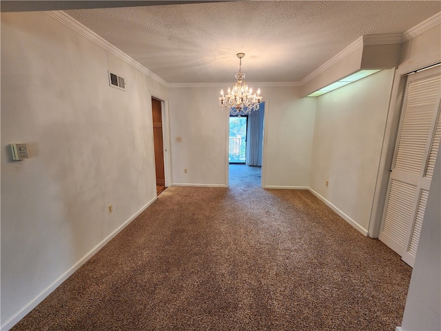 empty room featuring ornamental molding, a textured ceiling, a notable chandelier, and carpet flooring