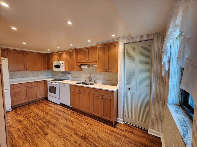 kitchen with backsplash, sink, light hardwood / wood-style flooring, and white appliances