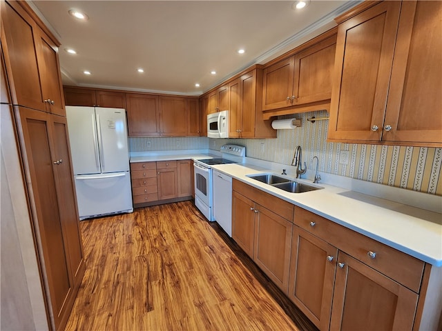 kitchen featuring sink, light wood-type flooring, white appliances, and tasteful backsplash