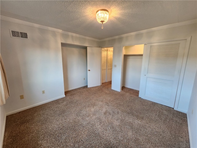 unfurnished bedroom featuring multiple closets, a textured ceiling, crown molding, and carpet flooring