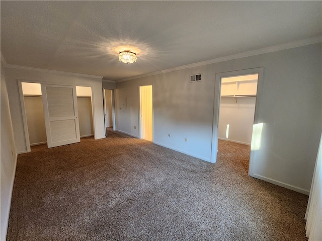 unfurnished bedroom with a closet, crown molding, carpet floors, and a walk in closet