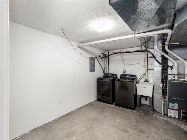 basement with a textured ceiling, electric panel, sink, and washing machine and dryer