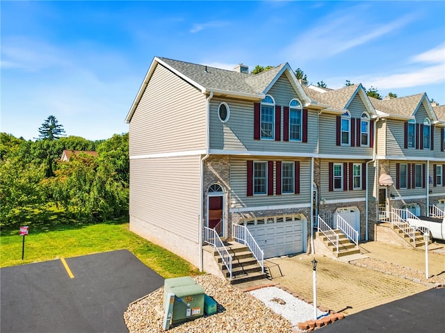 multi unit property featuring a front lawn and a garage