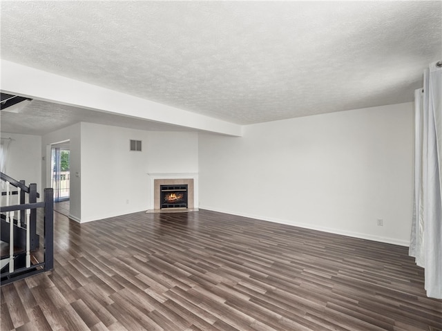 unfurnished living room with a textured ceiling, a tiled fireplace, and dark hardwood / wood-style flooring