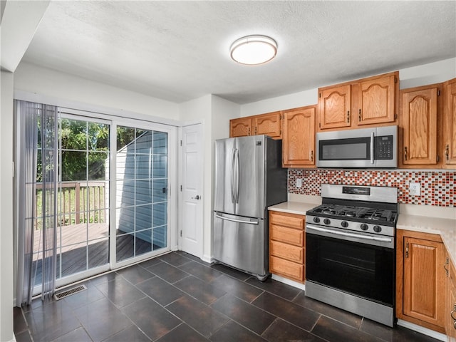 kitchen featuring a textured ceiling, stainless steel appliances, and tasteful backsplash