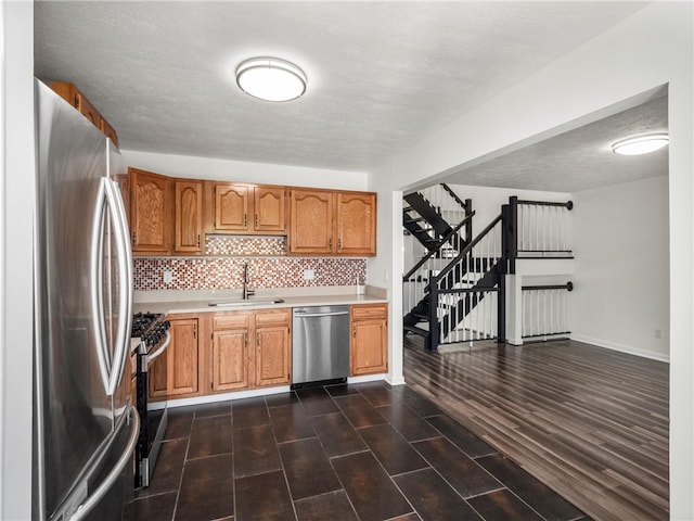 kitchen featuring stainless steel appliances, a textured ceiling, sink, and dark hardwood / wood-style flooring