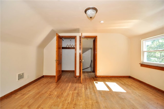 unfurnished bedroom with vaulted ceiling and light hardwood / wood-style floors