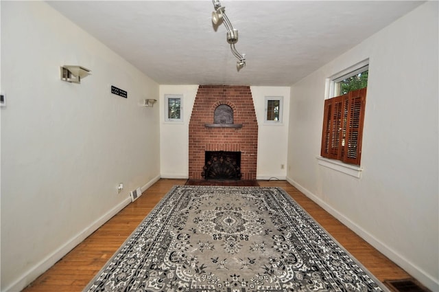 living room featuring a brick fireplace and wood-type flooring