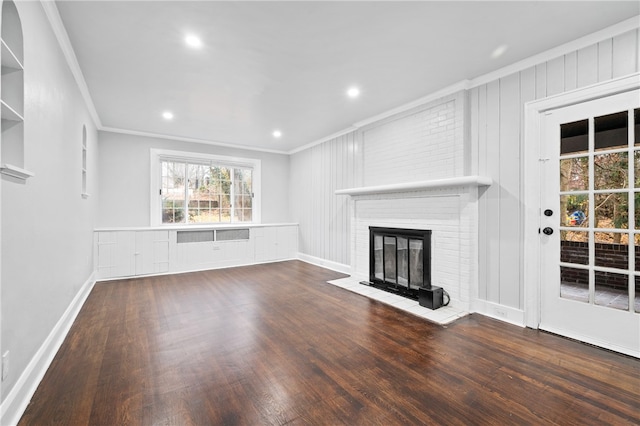 unfurnished living room with dark hardwood / wood-style floors, crown molding, and a brick fireplace