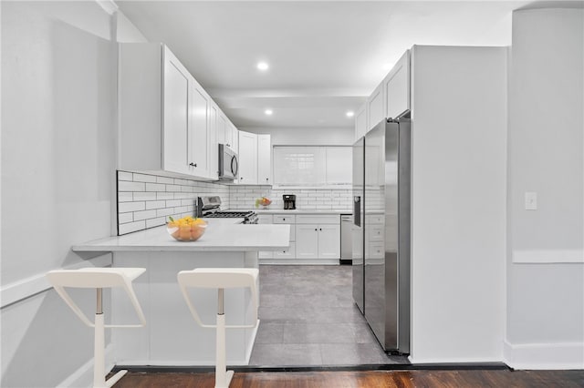 kitchen featuring decorative backsplash, appliances with stainless steel finishes, hardwood / wood-style flooring, and white cabinets