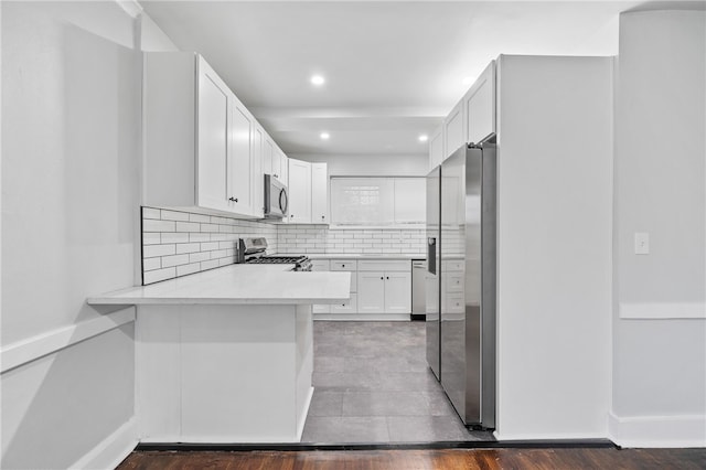 kitchen featuring white cabinetry, stainless steel appliances, kitchen peninsula, and hardwood / wood-style flooring