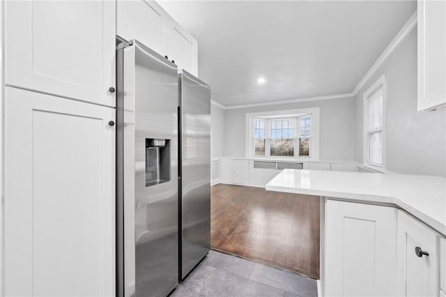 kitchen with light wood-type flooring, ornamental molding, stainless steel fridge with ice dispenser, and white cabinets