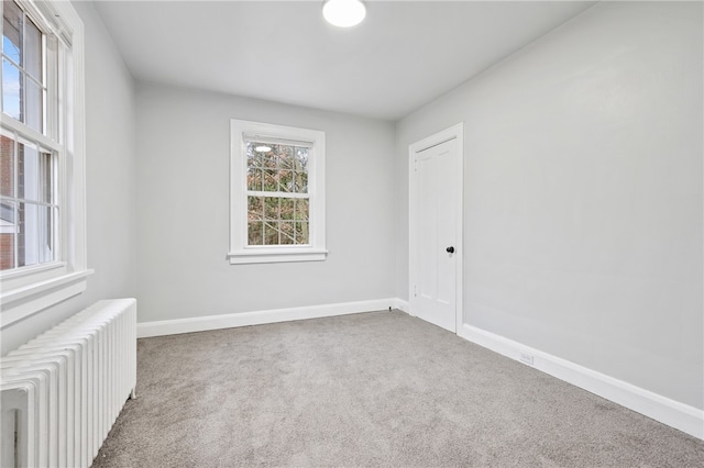 unfurnished room with radiator and carpet floors