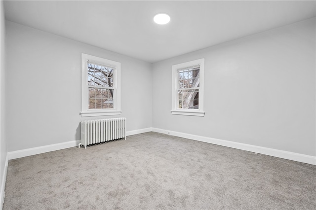 spare room with radiator heating unit and carpet flooring