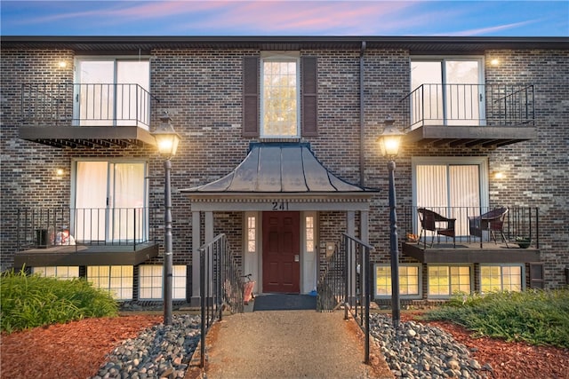 view of front of house featuring a standing seam roof and brick siding