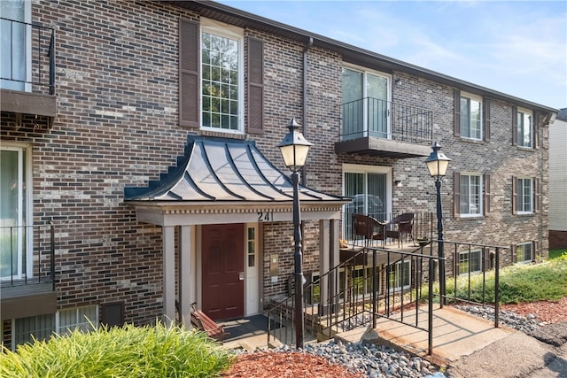 townhome / multi-family property featuring a standing seam roof, metal roof, and brick siding