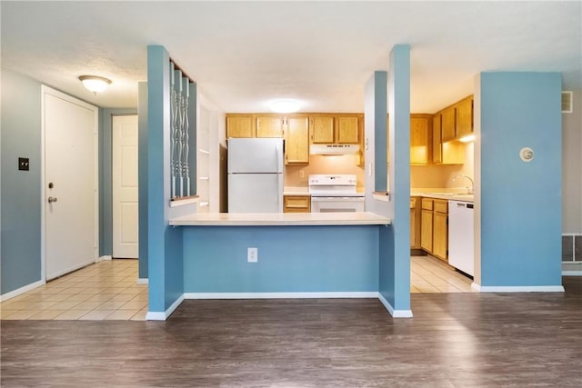 kitchen with white appliances, baseboards, light wood-style flooring, light countertops, and under cabinet range hood