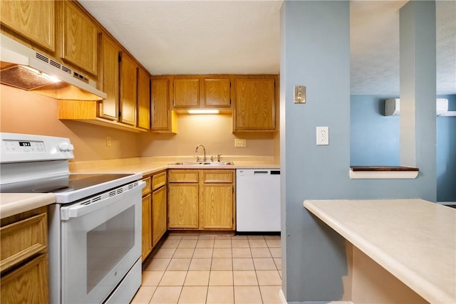 kitchen with white appliances, light tile patterned floors, light countertops, under cabinet range hood, and a sink