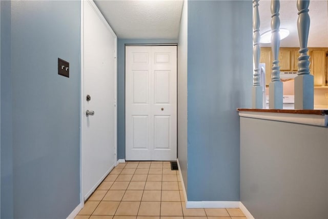 entryway featuring a textured ceiling, light tile patterned floors, and baseboards