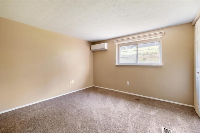 carpeted empty room with an AC wall unit, visible vents, a textured ceiling, and baseboards