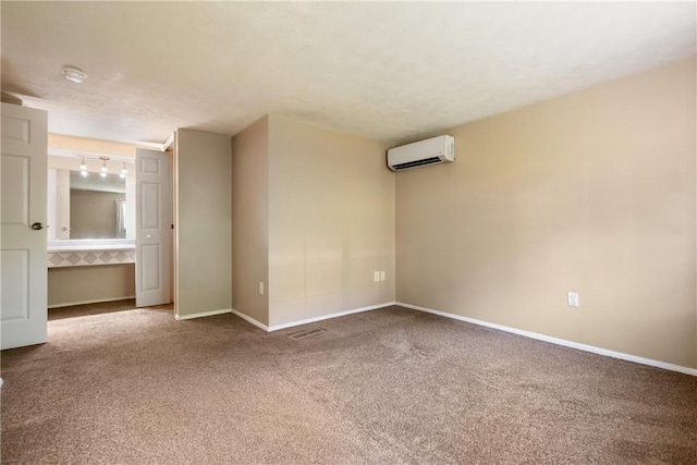 spare room featuring an AC wall unit, carpet, visible vents, and baseboards