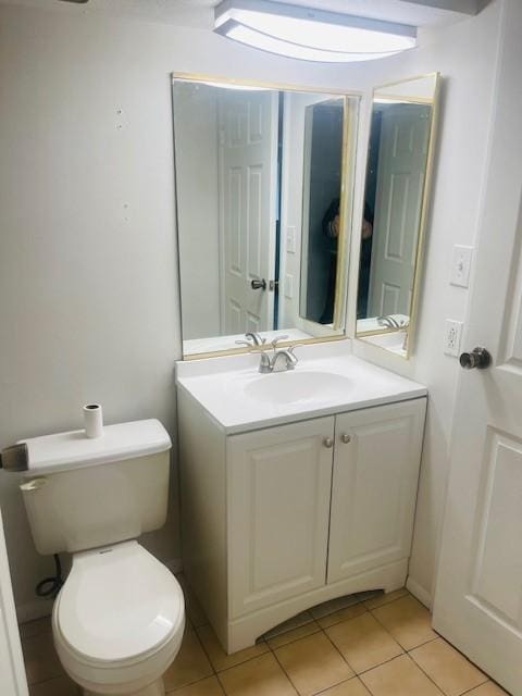 half bathroom with vanity, tile patterned flooring, and toilet