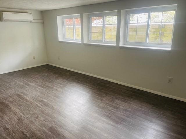 spare room featuring a wall mounted AC, wood finished floors, and baseboards