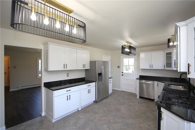 kitchen with appliances with stainless steel finishes, white cabinetry, baseboard heating, and sink