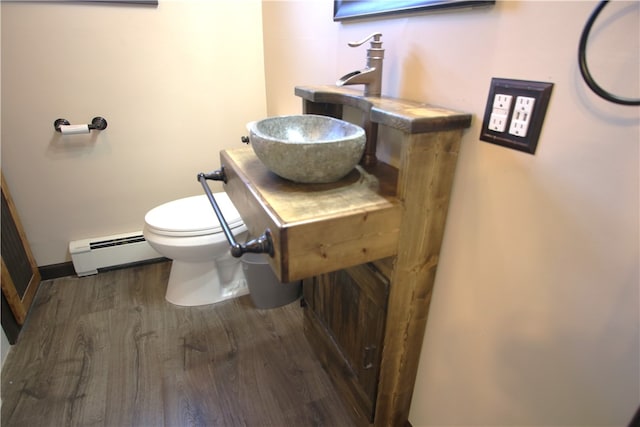 bathroom with toilet, baseboard heating, and hardwood / wood-style flooring