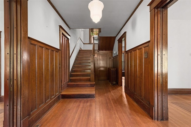 staircase with hardwood / wood-style floors, wood walls, and ornamental molding