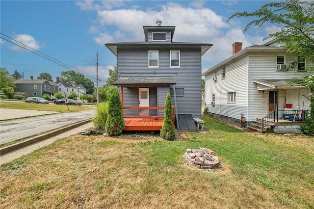 back of house featuring a yard, a deck, and an outdoor fire pit