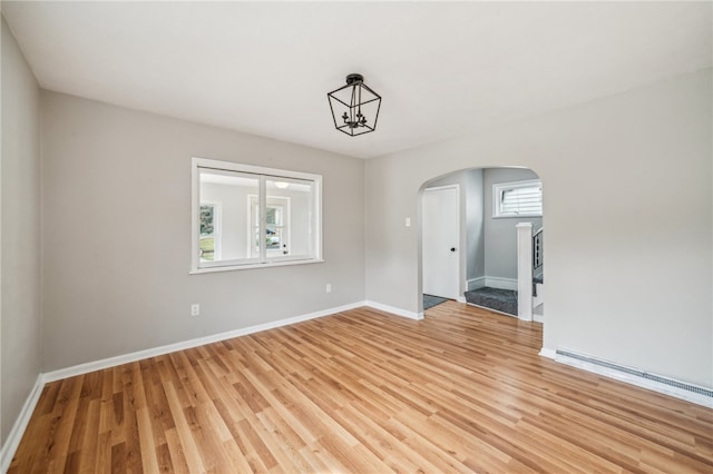 unfurnished room featuring a baseboard radiator and light hardwood / wood-style floors