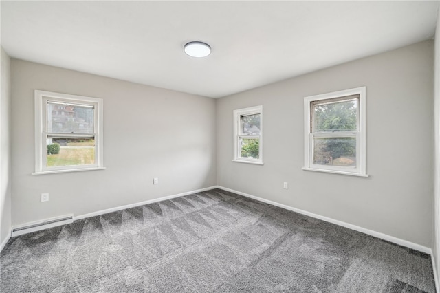 empty room with a baseboard heating unit, a wealth of natural light, and carpet flooring