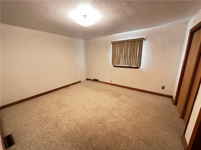 spare room featuring a textured ceiling and light colored carpet