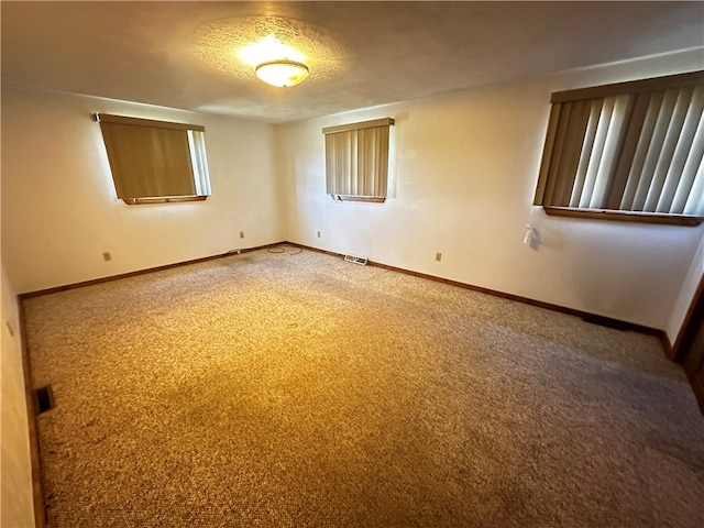 carpeted empty room featuring a textured ceiling and a healthy amount of sunlight