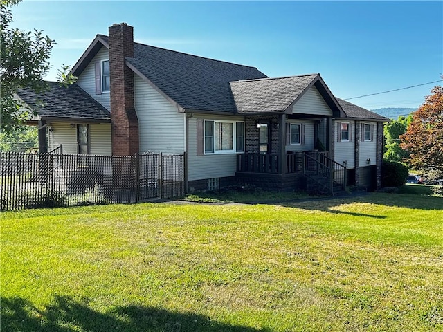 view of front of home with a shingled roof, a chimney, a front yard, and fence
