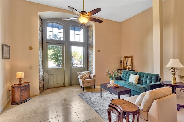 interior space with light tile patterned floors, baseboards, ceiling fan, and a towering ceiling