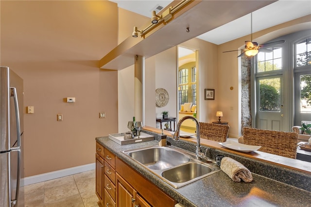 kitchen featuring hanging light fixtures, sink, stainless steel refrigerator, and ceiling fan