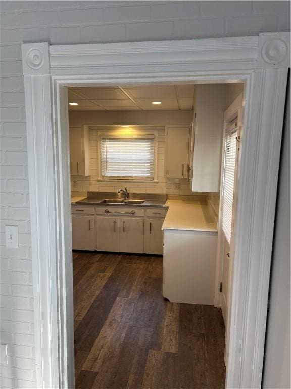 kitchen with dark wood finished floors, light countertops, white cabinets, and a sink