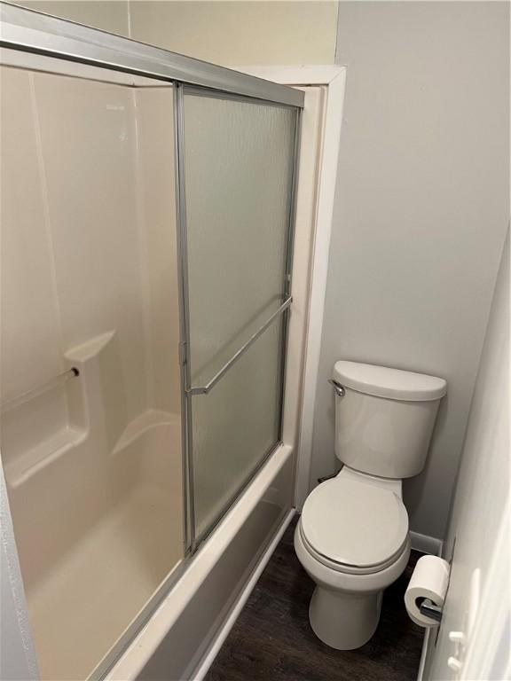 full bath with an enclosed shower, toilet, and wood finished floors