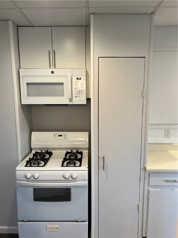 kitchen featuring white appliances and a drop ceiling