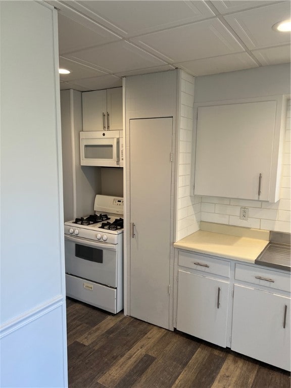 kitchen featuring white appliances, dark hardwood / wood-style flooring, white cabinets, and tasteful backsplash