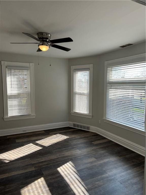 unfurnished room featuring wood finished floors, visible vents, and baseboards