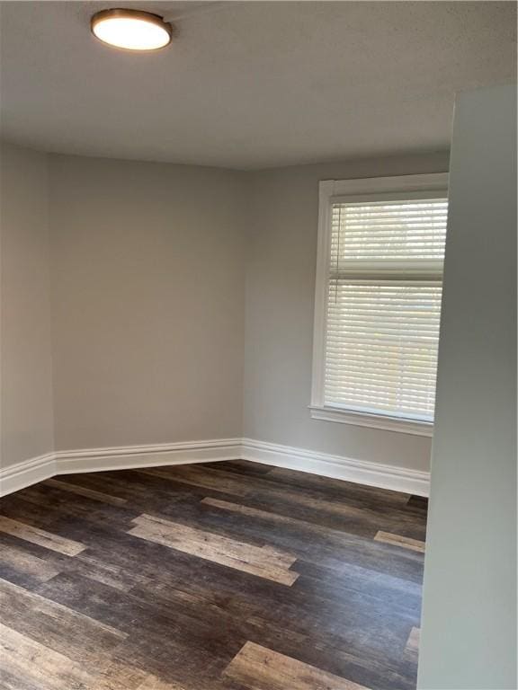 unfurnished room with dark wood-style floors and baseboards